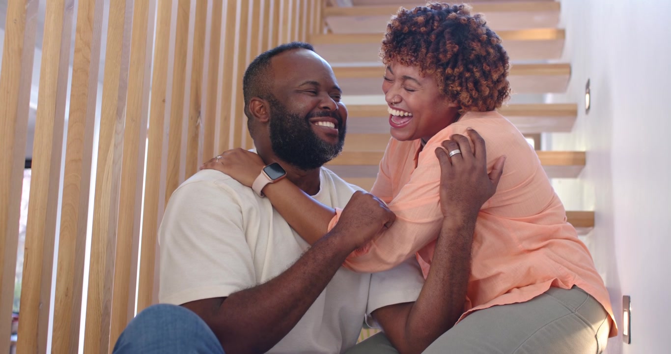 African American couple sharing affection, woman leaning over hugging man on stairs, ring, watch