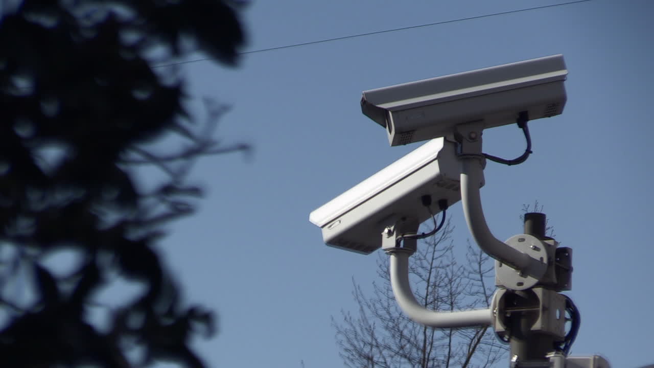 close up of a surveillance camera against blue sky, watching every move