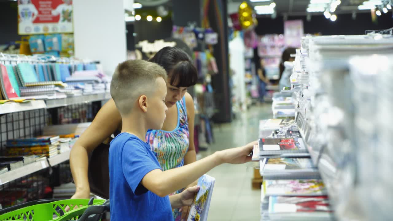 VINNITSA, UKRAINE - AUGUST 20, 2018: Back to school concept. Young mother and little boy buying school supplies in store.