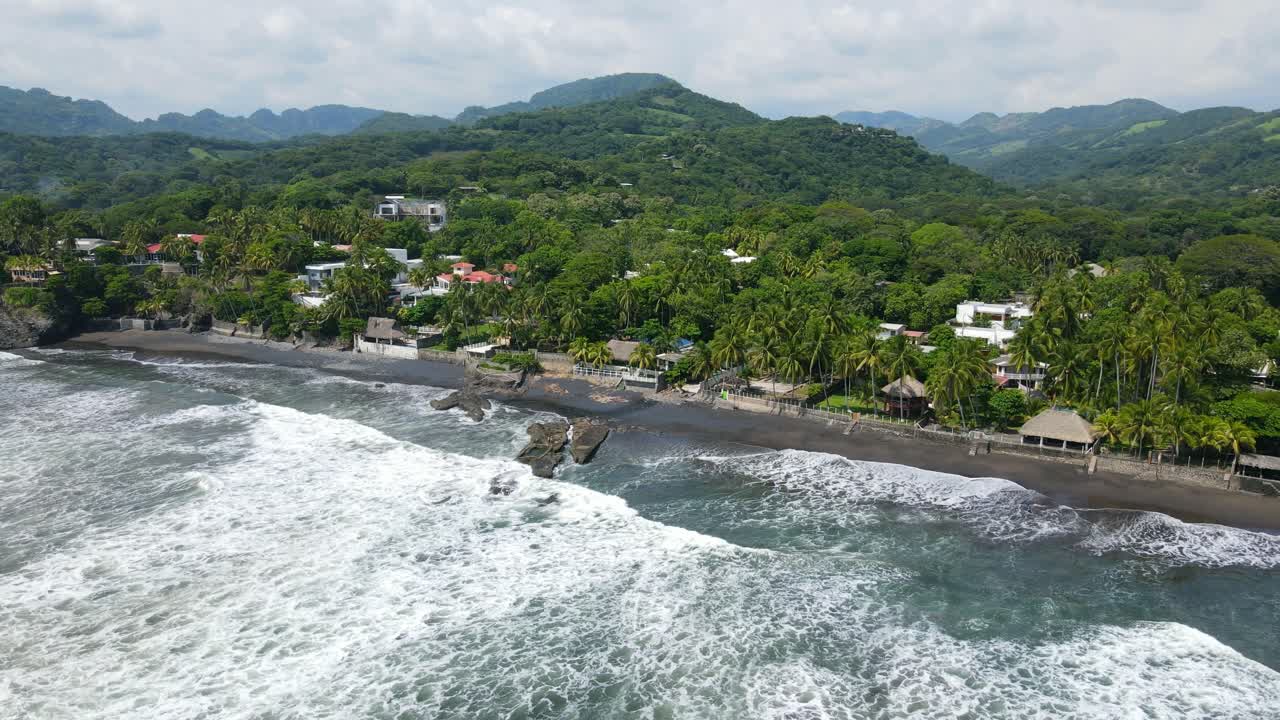 vista aérea moviéndose a la derecha, olas corriendo hacia la costa de la playa bitcoin en el salvador, méxico, vista panorámica de una cordillera en el fondo