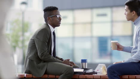 businessman sitting on a break while having breakfast and talking to an coworker