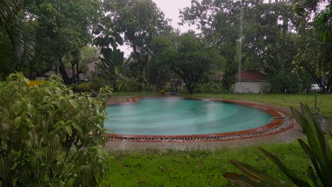 rain falls into private backyard pool in goa, indian during monsoon season