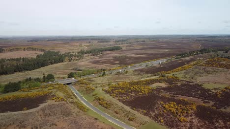 Highway-in-the-countryside-newforest-uk,-motorway-moving-cars-aerial-shot-cinematic