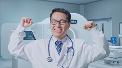close up of asian male doctor smile and flex muscle with mri machine in the hospital