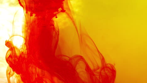 pintura o tinte rojo y amarillo caído en el agua contra un fondo blanco para crear un fondo de humo de colores giratorios 1