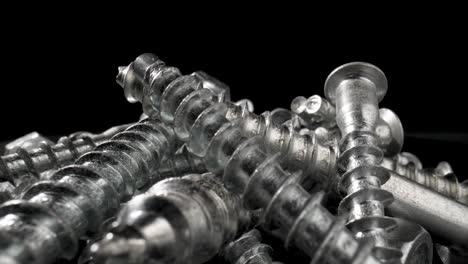 close-up of various silver metal screws on a black background