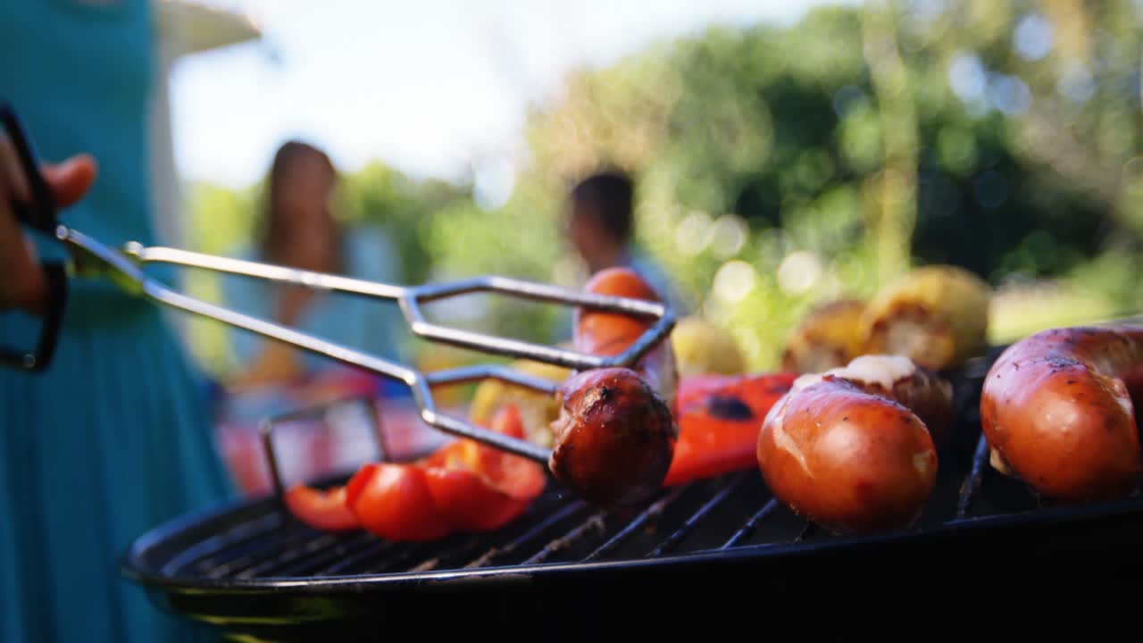 Girl flipping sausages on barbecue