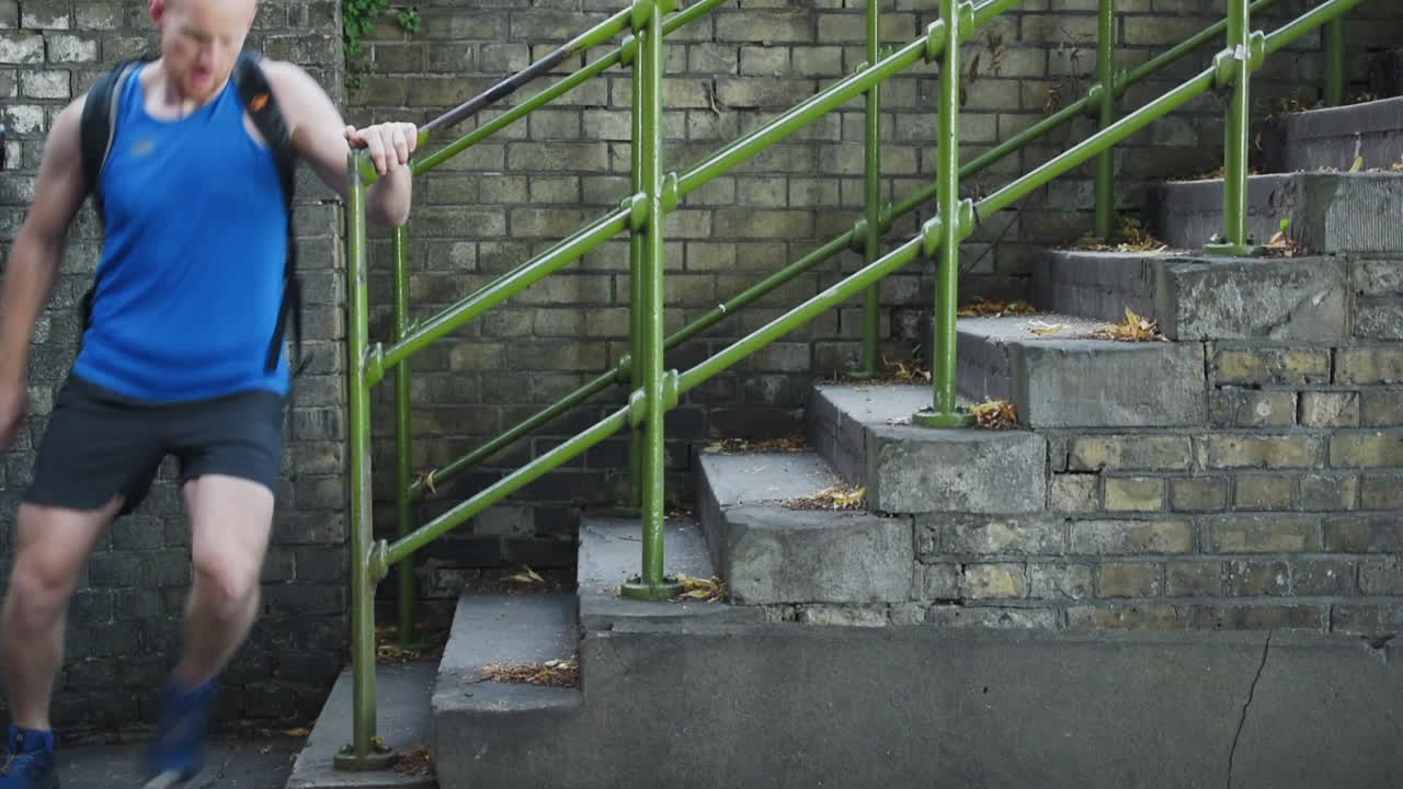 Man runs down outdoor stairs in slow motion, runner in a hurry