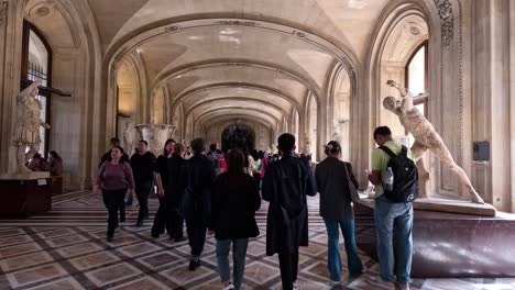 people walking through louvre museum's grand hallway