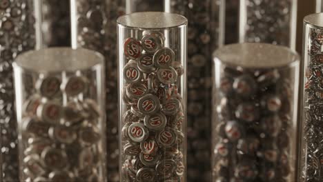 intricate close-up of glass containers filled with metallic bottle caps displaying unique numbers, showcasing the art of collecting and preservation