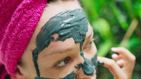 Junge-Frau-Mit-Handtuch-Auf-Dem-Kopf,-Die-Sich-Nach-Der-Dusche-Im-Tropischen-Bali-badezimmer-Eine-Gesichtsmaske-Auflegt