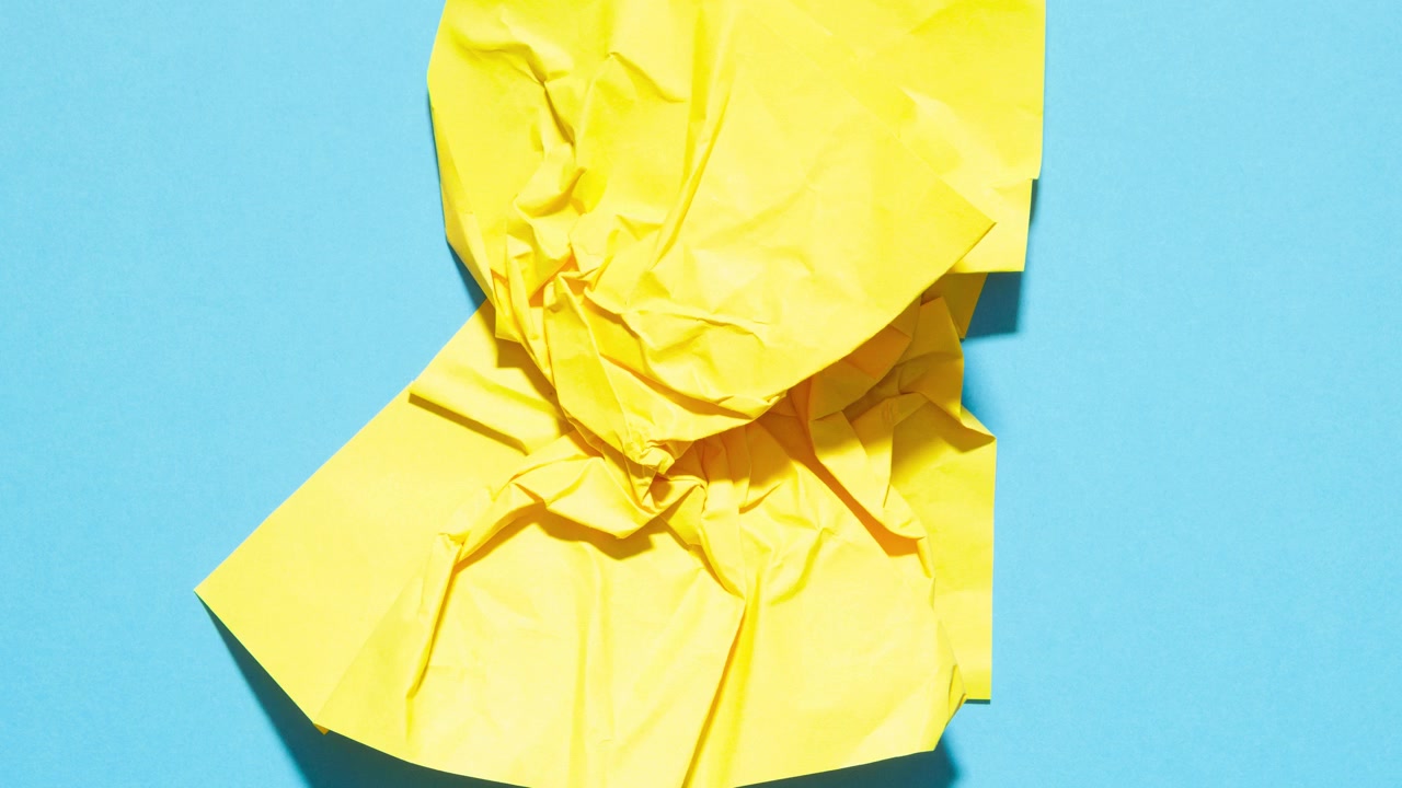 Carta gialla stropicciata che si apre e si richiude su sfondo blu in transizione stop motion