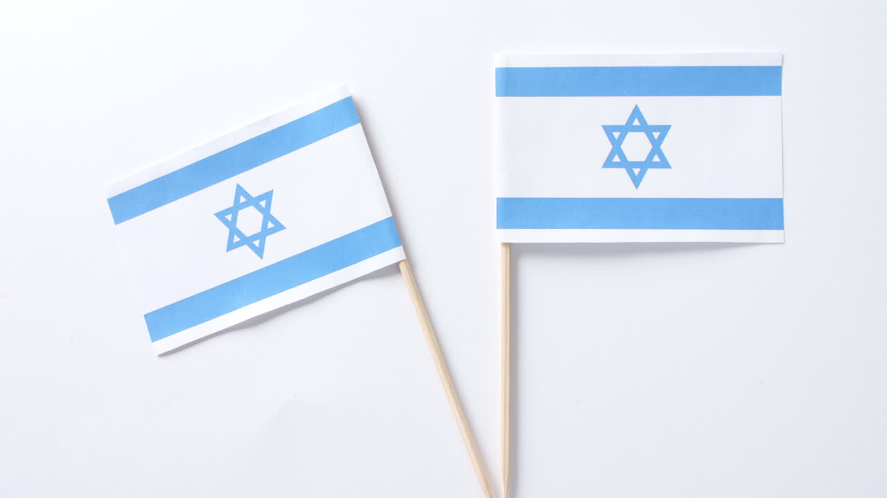 Primo piano di due bandiere di Israele adagiate su sfondo bianco.