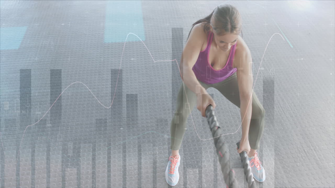 animación de procesamiento de datos en gráfico sobre mujer caucásica entrenamiento cruzado con cuerdas de batalla en el gimnasio