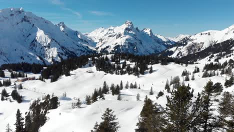 Drone-view-of-skiers-enjoying-the-snow-covered-mountain-ranges-in-Warth,-a-small-municipality-in-Vorarlberg,-Austria-in-4K