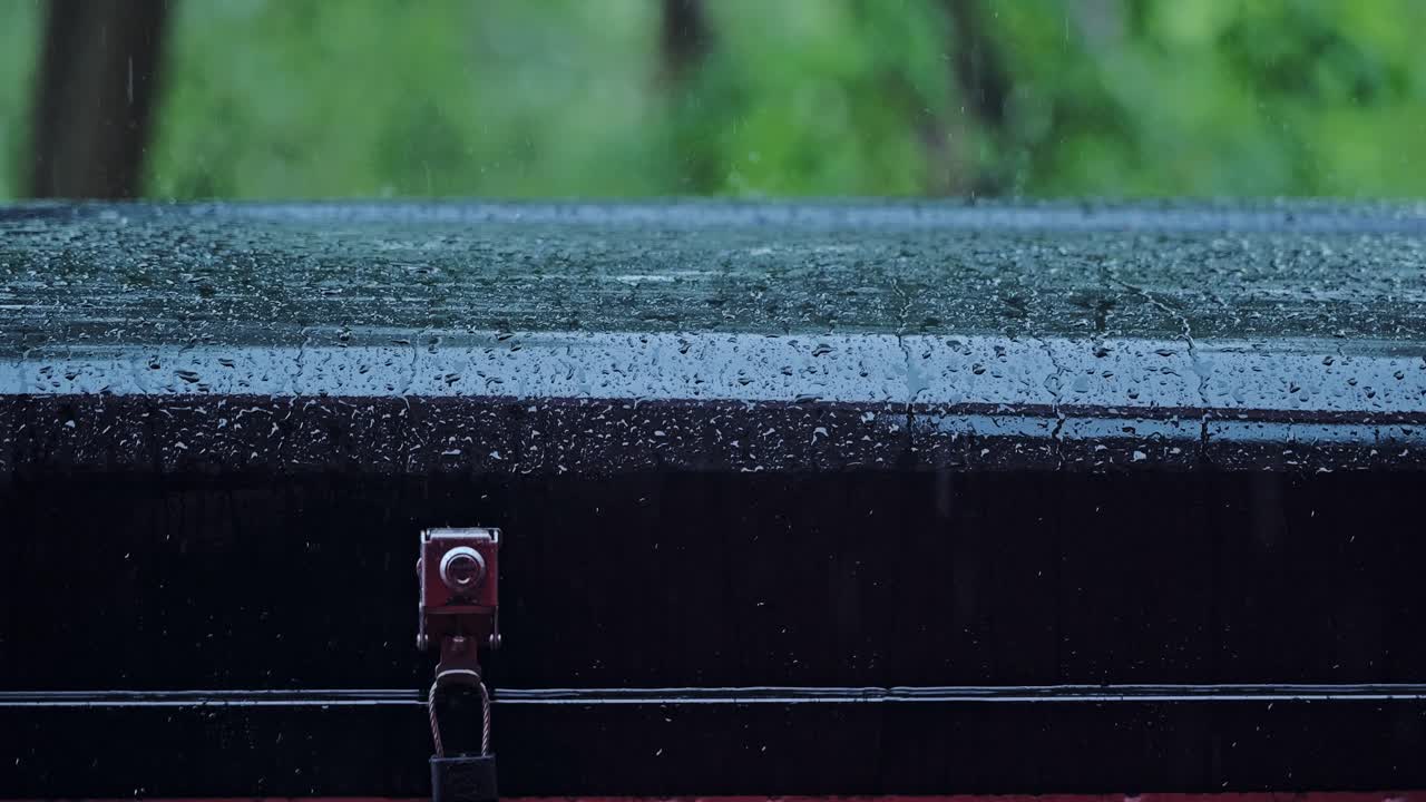 Detail shot of tent roof as rain beads burst, trickle down in slow motion