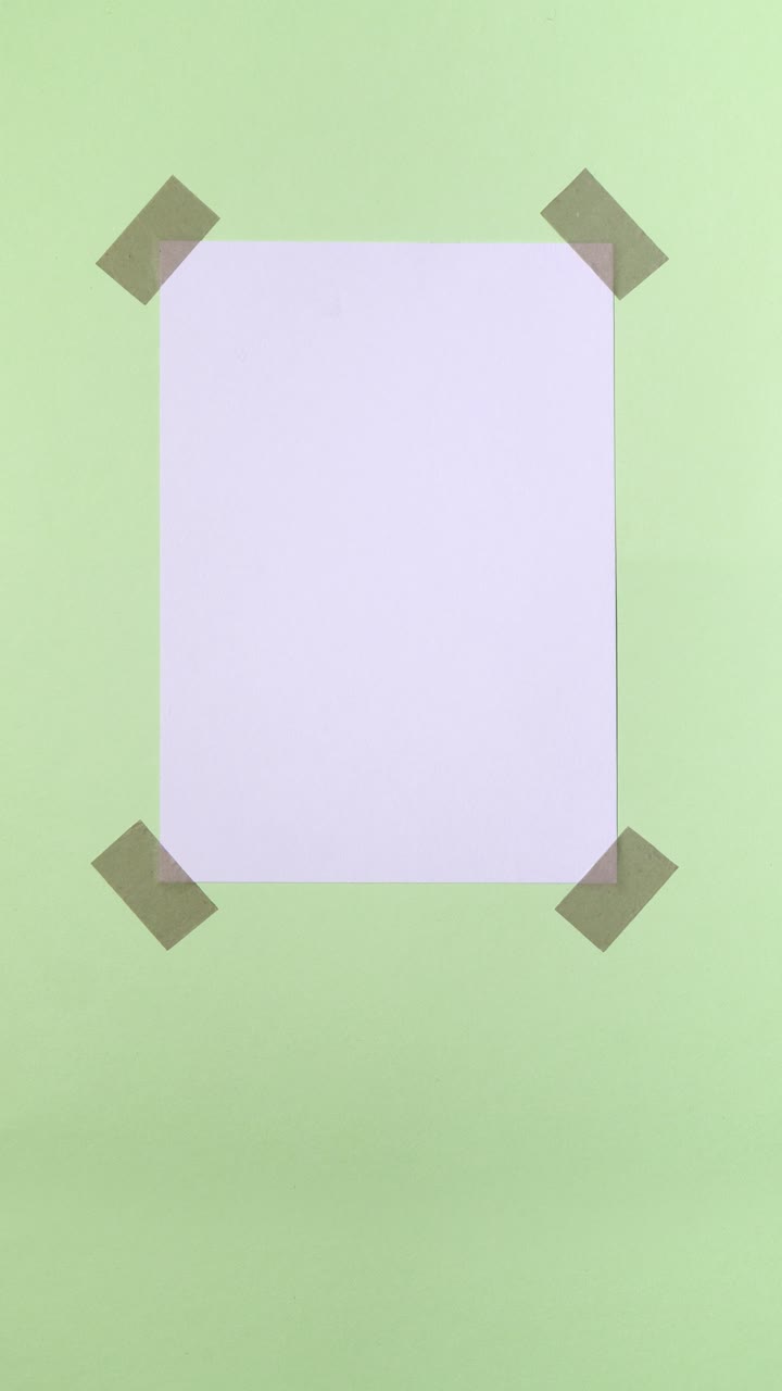 White paper note appears and is taped onto a pastel green background in a vertical stop motion loop with copy space