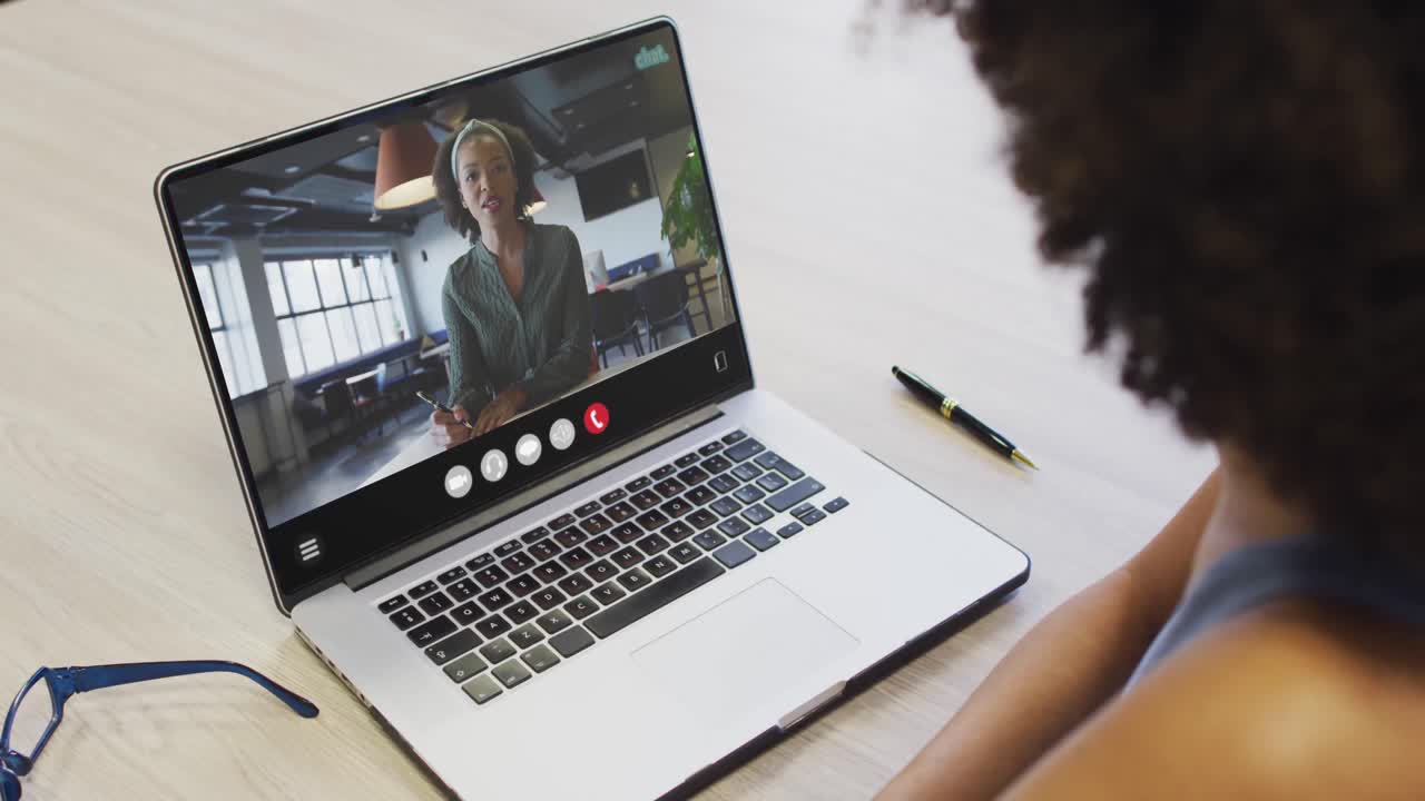 African american woman using laptop for video call, with business colleague on screen