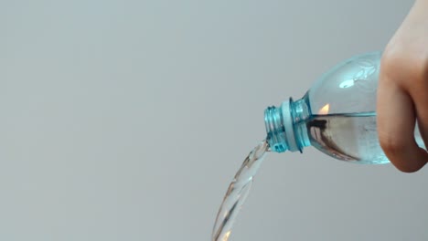 pouring out water of transparent blue plastic bottle