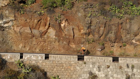 Un-Caballero-Con-Una-Camiseta-Amarilla-Anda-En-Bicicleta-En-Una-Bicicleta-Deportiva-De-Carretera-Por-Una-Carretera-Situada-A-Gran-Altura-En-Las-Montañas