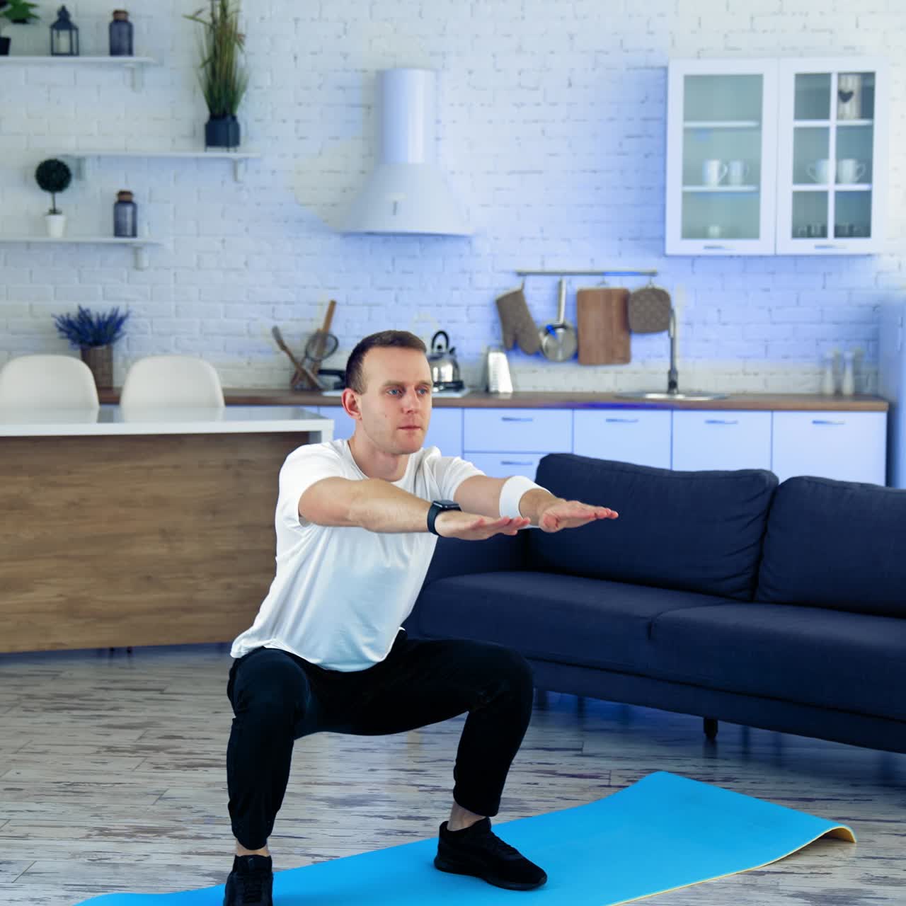 Sportman doing exercise at home. Man doing squats and exercising in living room at home