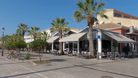 pan from sunny restaurant terraces to promenade, preveza, greece