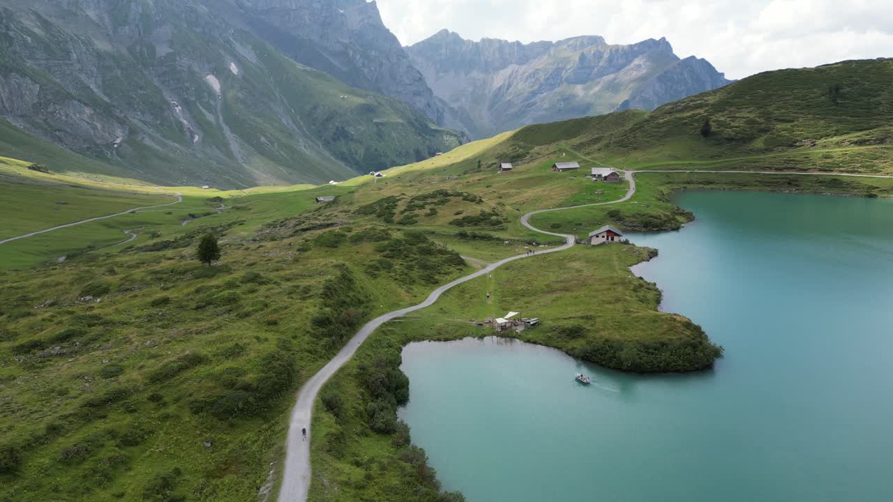 empuje: vista aérea de drones de la orilla de un lago alpino y un camino sinuoso para que la gente admire la vista, montañas rocosas en el fondo, obwalden, engelberg