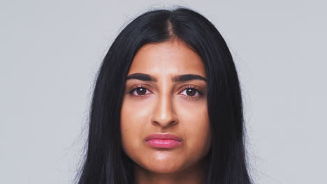 head and shoulders studio shot of woman looking at camera with serious expression in slow motion