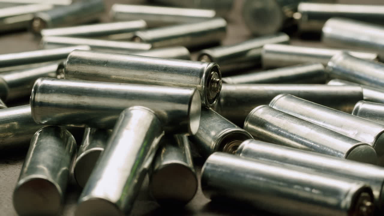 Silver batteries AA and AAA on black background close-up. Double-A battery is a standard size single cell cylindrical dry battery. Batteries are common in portable electronic devices. An AA battery is composed of a single electrochemical cell that may be either a primary battery or a rechargeable ba