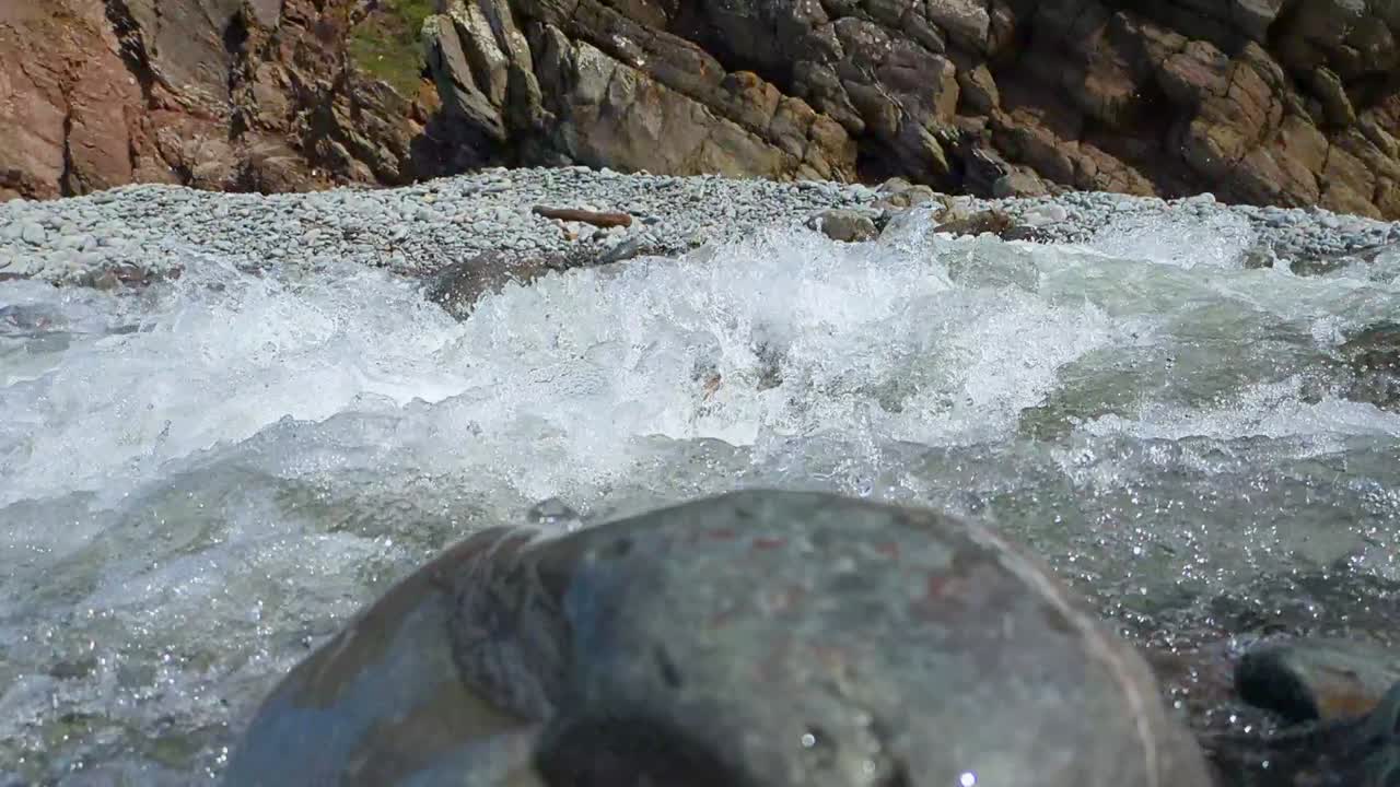 Fast River on Pebble Beach Flowing by in Slow Motion