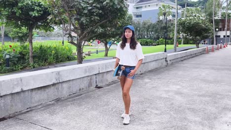 woman walking with a skateboard in a park