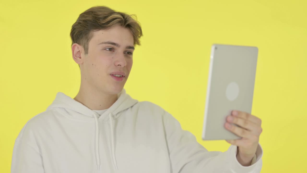 노란색 배경의 젊은이의 태블릿에서 비디오 채팅