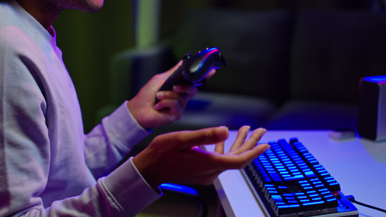 hombre jugando videojuegos con controlador y teclado por la noche