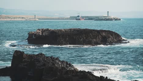 escena de mar y olas cerca de la ciudad de beirut con una pequeña isla en el medio.