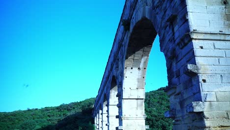 birds fly by and over the pont du gard in france in the sun