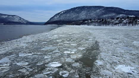 aerial drone footage of an icy river and snow-covered mountains during winter in america in the appalachian mountain range, after fresh snowfall