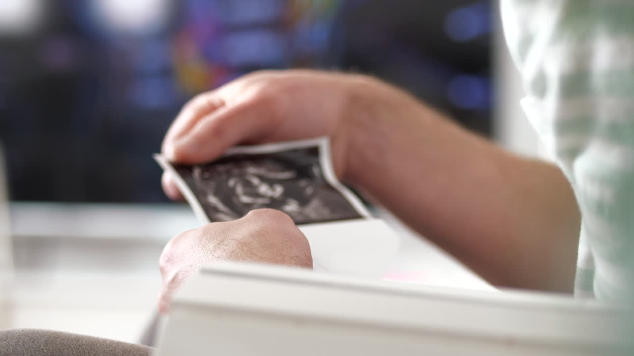 Unrecognizable father tenderly holds in hand ultrasound of future son or daughter