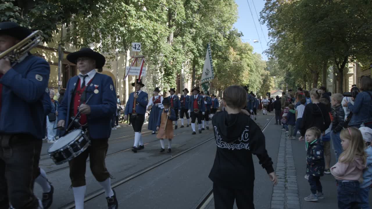 Handheld shot of Curious Child Captivated by the Passing Parade of People, at the Cannstatter Volksfest Historical Parade, in Stuttgart Bad Cannstatt, Baden-Württemberg, in Germany