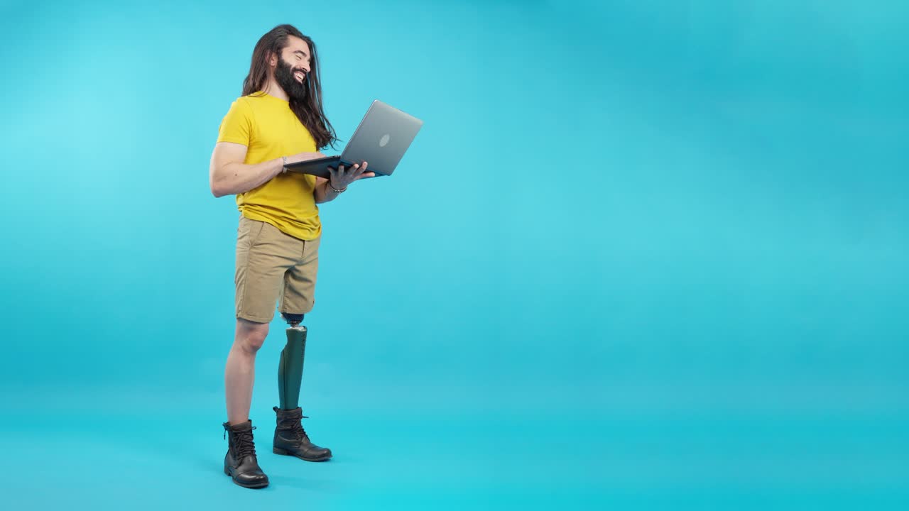 Man with prosthetic leg using a laptop in a studio
