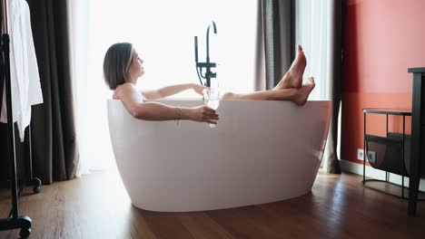 woman relaxing in a bathtub with a glass of wine