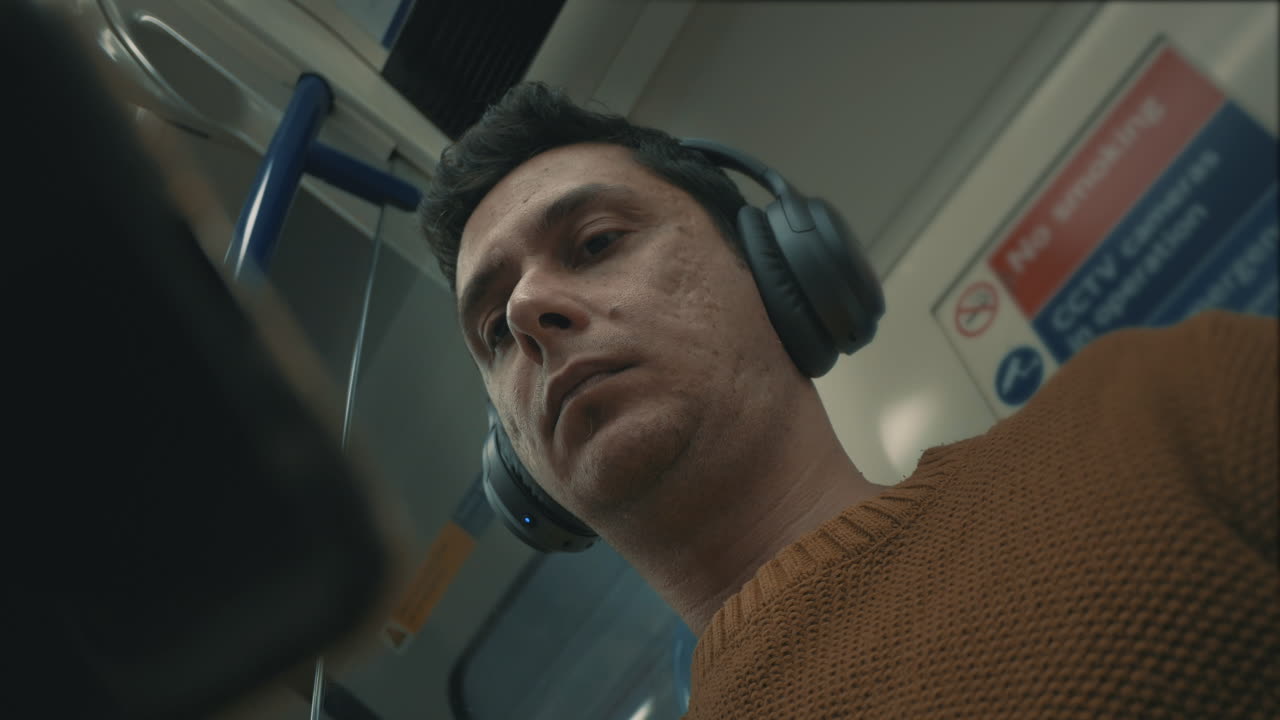 Commuter listens to music and reads while riding to work on the subway train