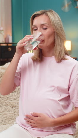Pregnant woman drinking pure water hand on belly showing hydration importance for healthy pregnancy