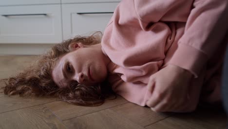 zoom in video of depressed young caucasian woman lying in the floor.