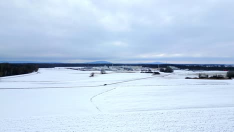 snow-covered field in austria near natural gas compressor station in winter