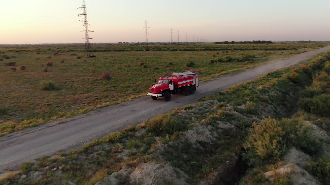 camión de bomberos rojo conduciendo por un camino de tierra entre campos en kiev, ucrania durante la puesta de sol dorada