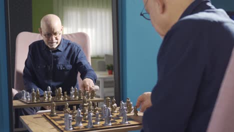 el viejo está jugando al ajedrez solo frente al espejo.