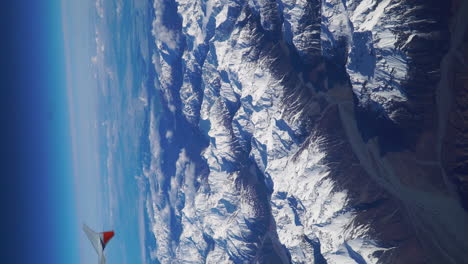 majestuoso paisaje montañoso con picos nevados desde la ventana del avión, video vertical