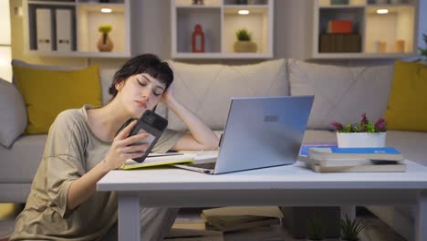 young woman lying on the sofa at night texting on the phone. happy and in good spirits.