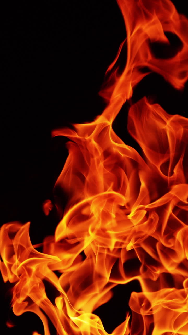Long fire flame rising up. Burning bonfire in the darkness isolated close up. Vertical video