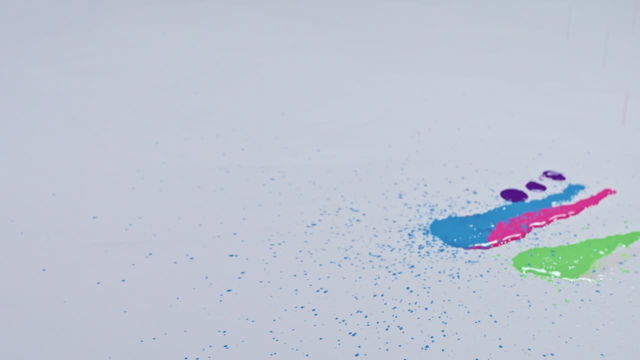 Vari colori gocciolano su uno sfondo bianco.